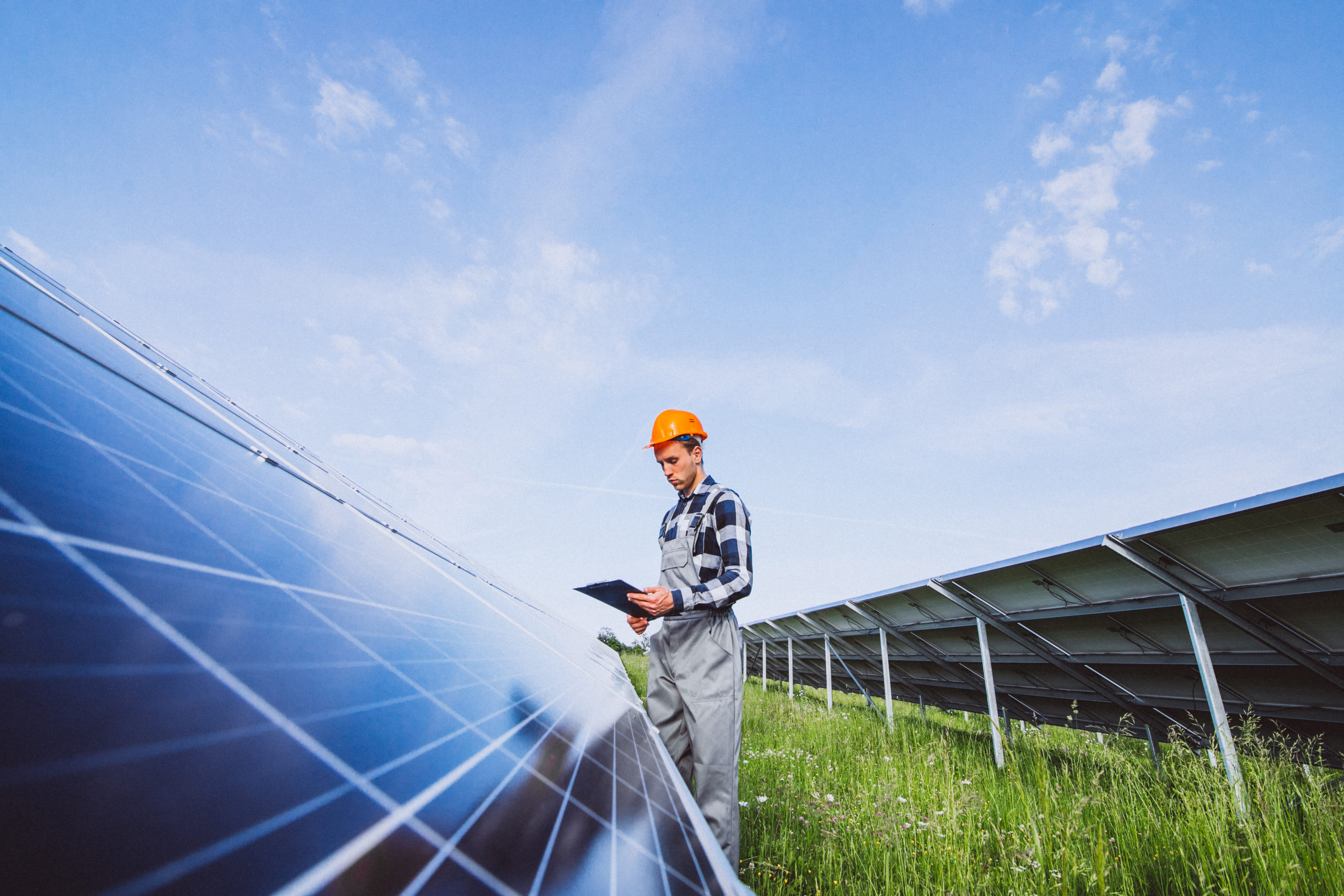 Engineer in headscarf and PPE reviewing technical standards of wind turbines onsite.