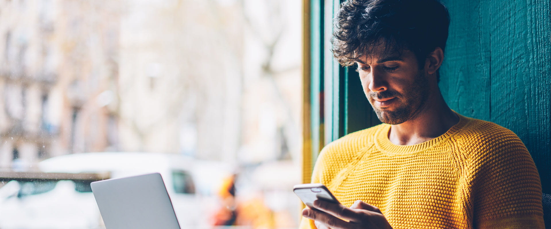 man in yellow sweater looking at tablet