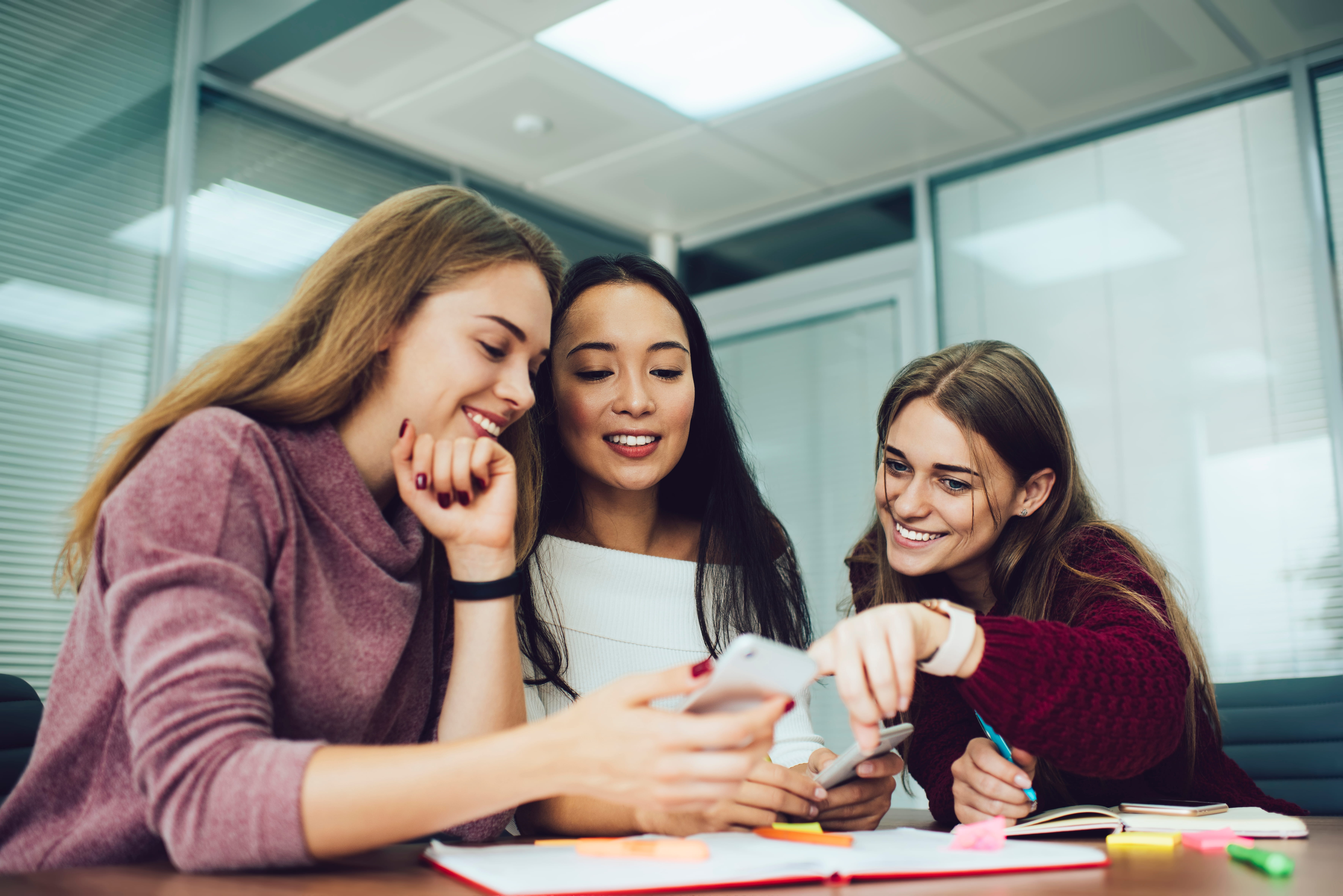 three professional women sitting at table looking at laptop