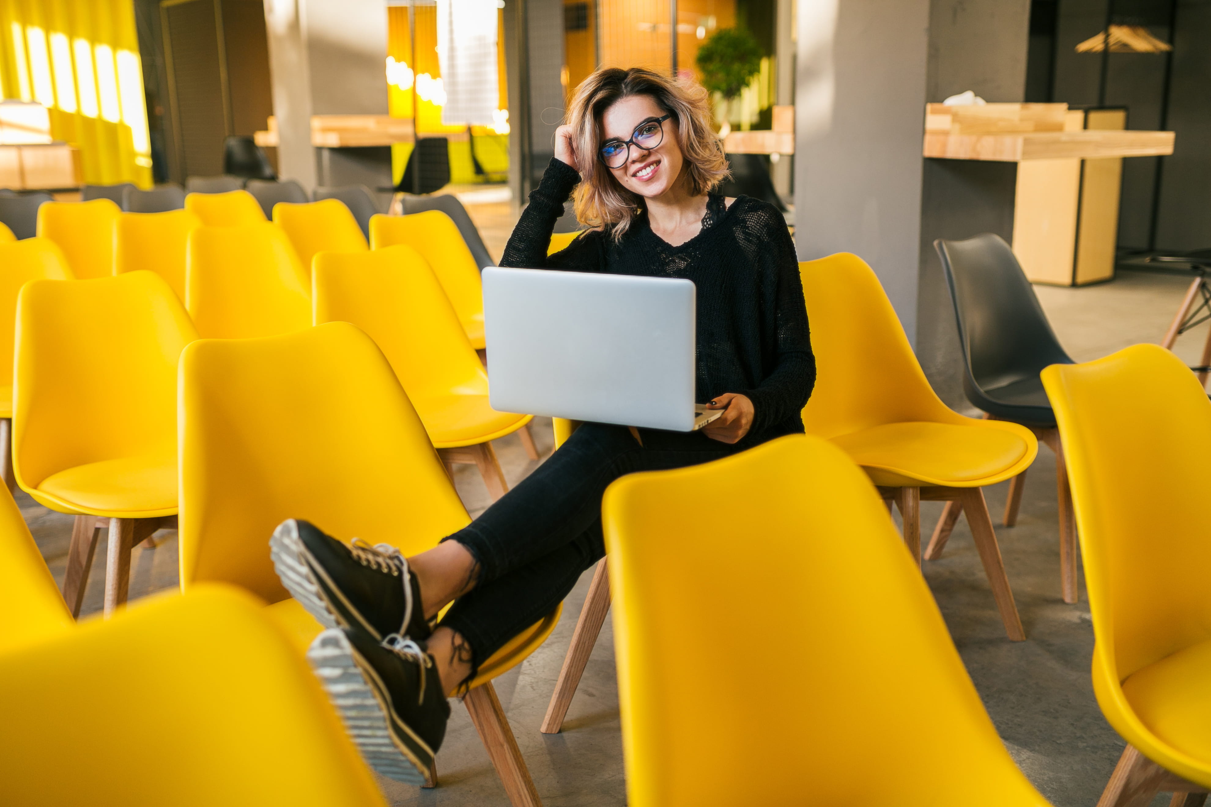 woman sitting on yellow chair holding laptop