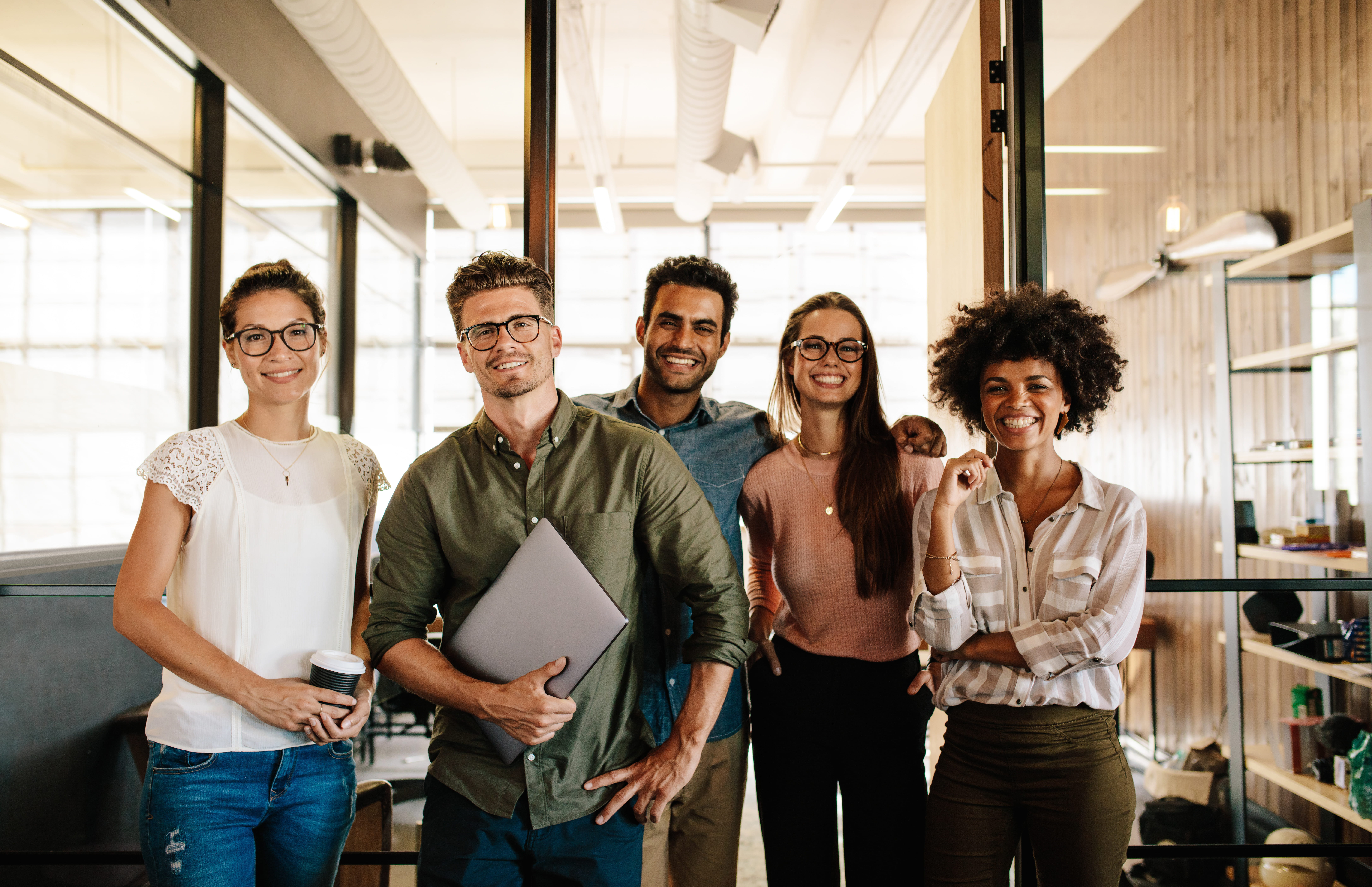 group of five professionals in office looking at camera