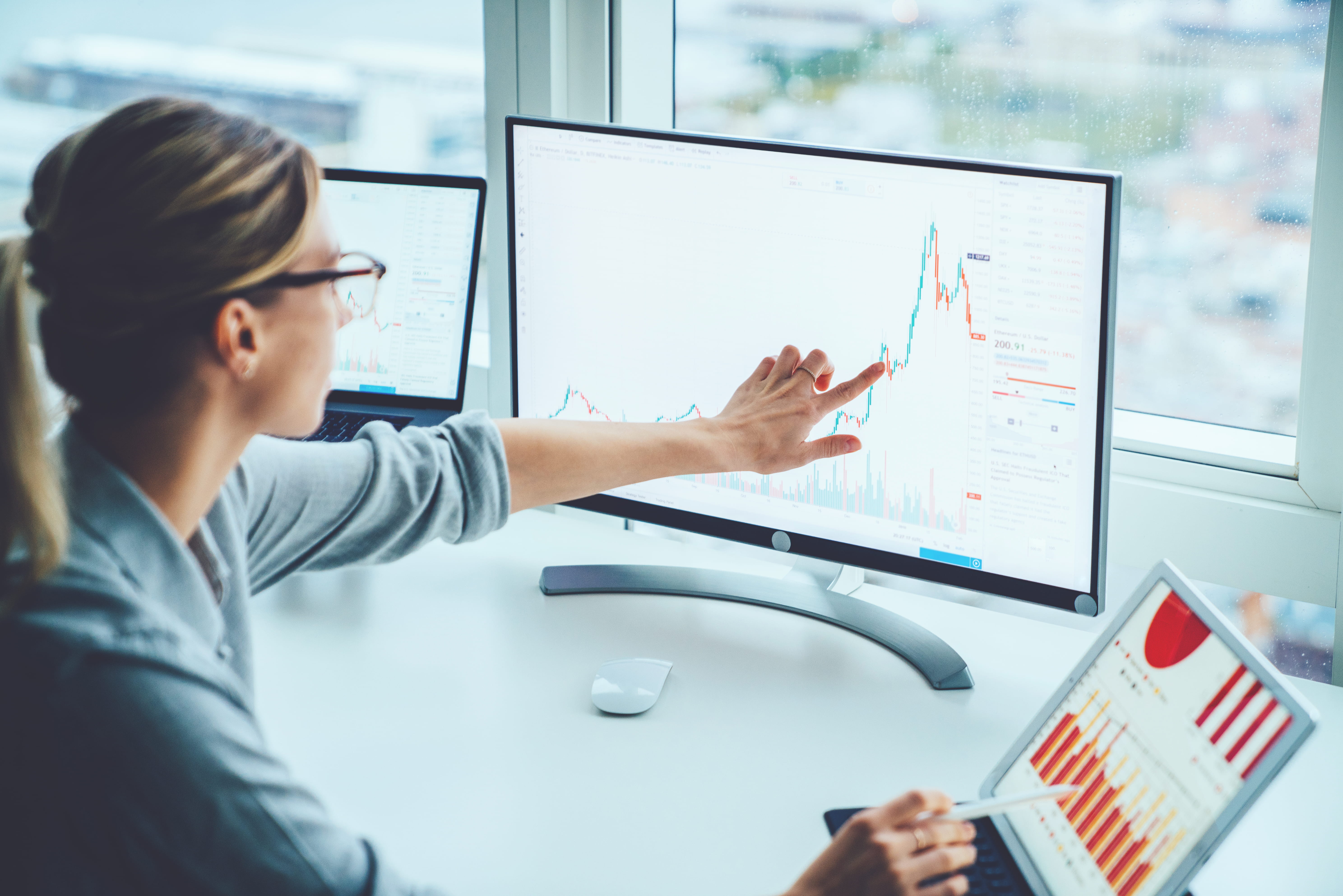 Finance analysts at a big 5 Canadian bank review investment portfolios and economic data on a tablet computer.